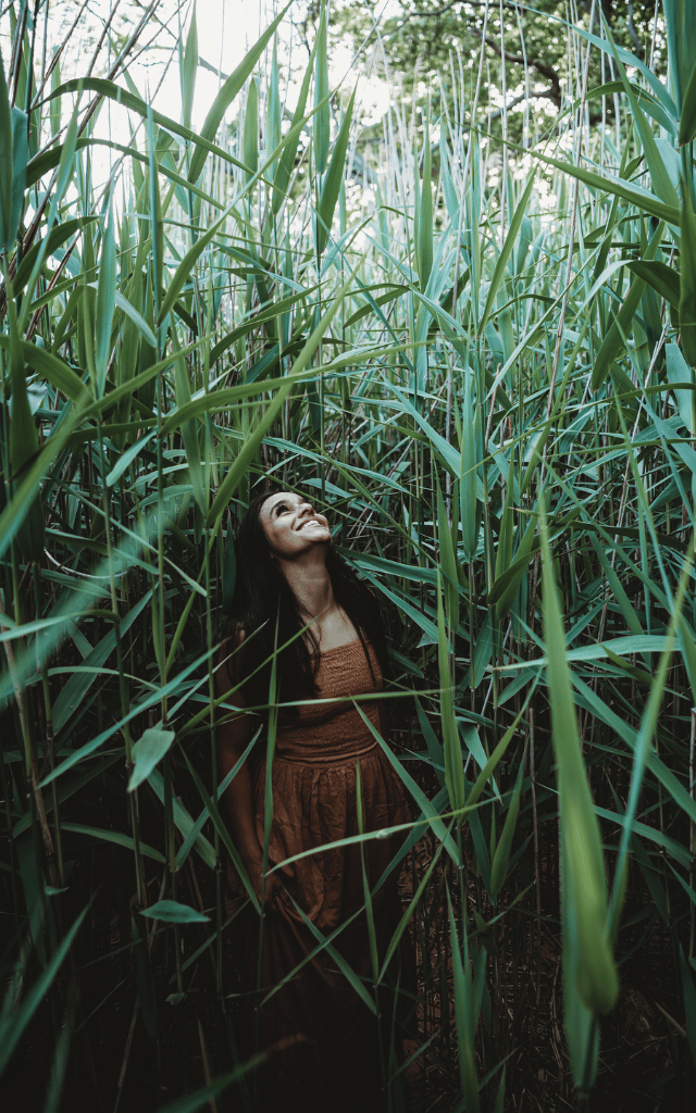 woman amongst tall reeds looking up 